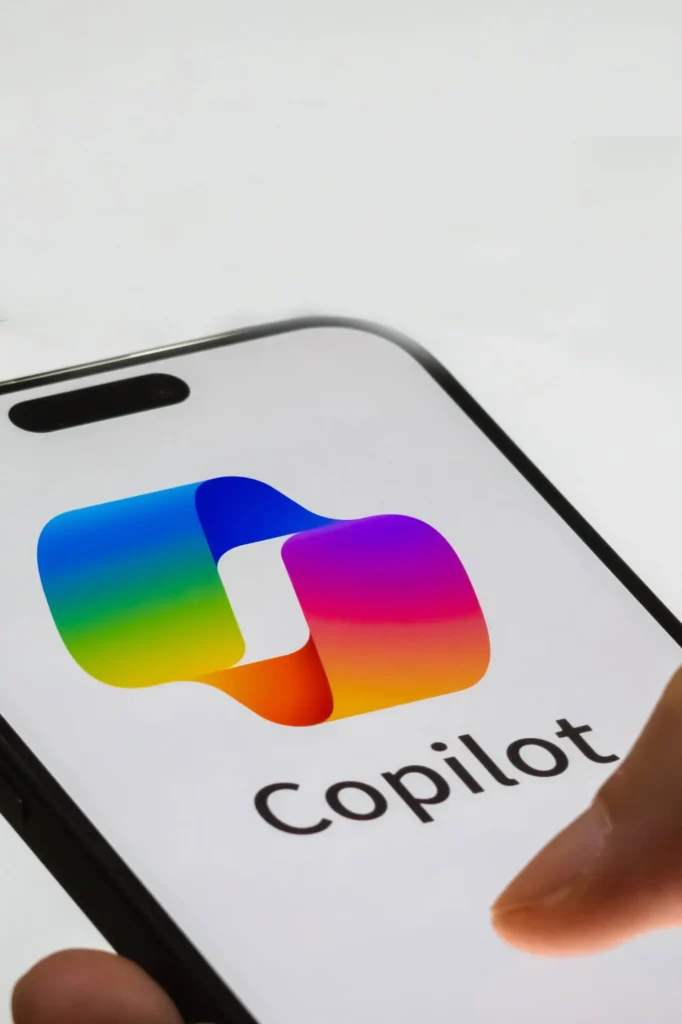 Ein Finger berührt den Bildschirm eines Telefons, auf dem das Logo der Copilot-App inmitten von Werbung angezeigt wird.