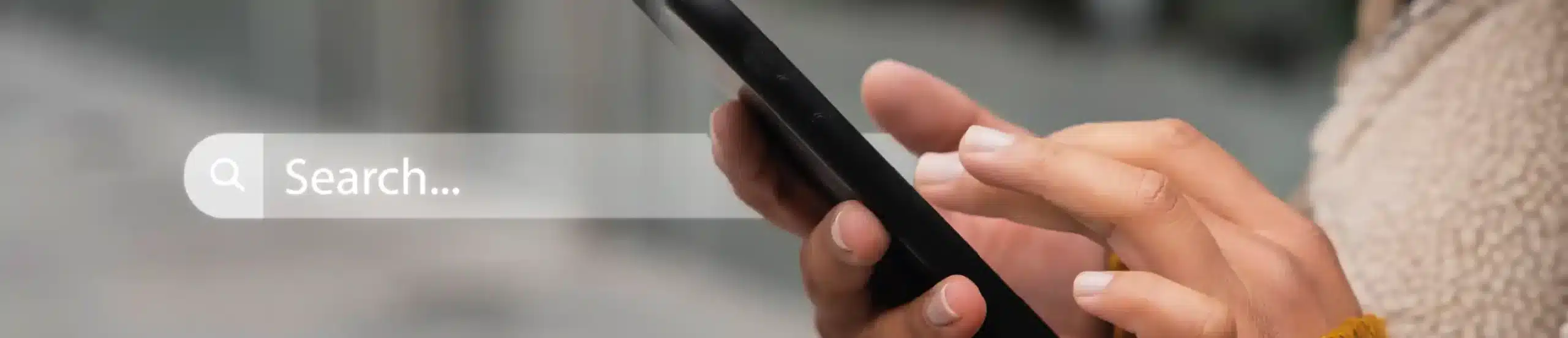 Hände, die ein Smartphone halten, auf dessen linker Seite eine Suchleiste für Display-Werbung eingeblendet ist.