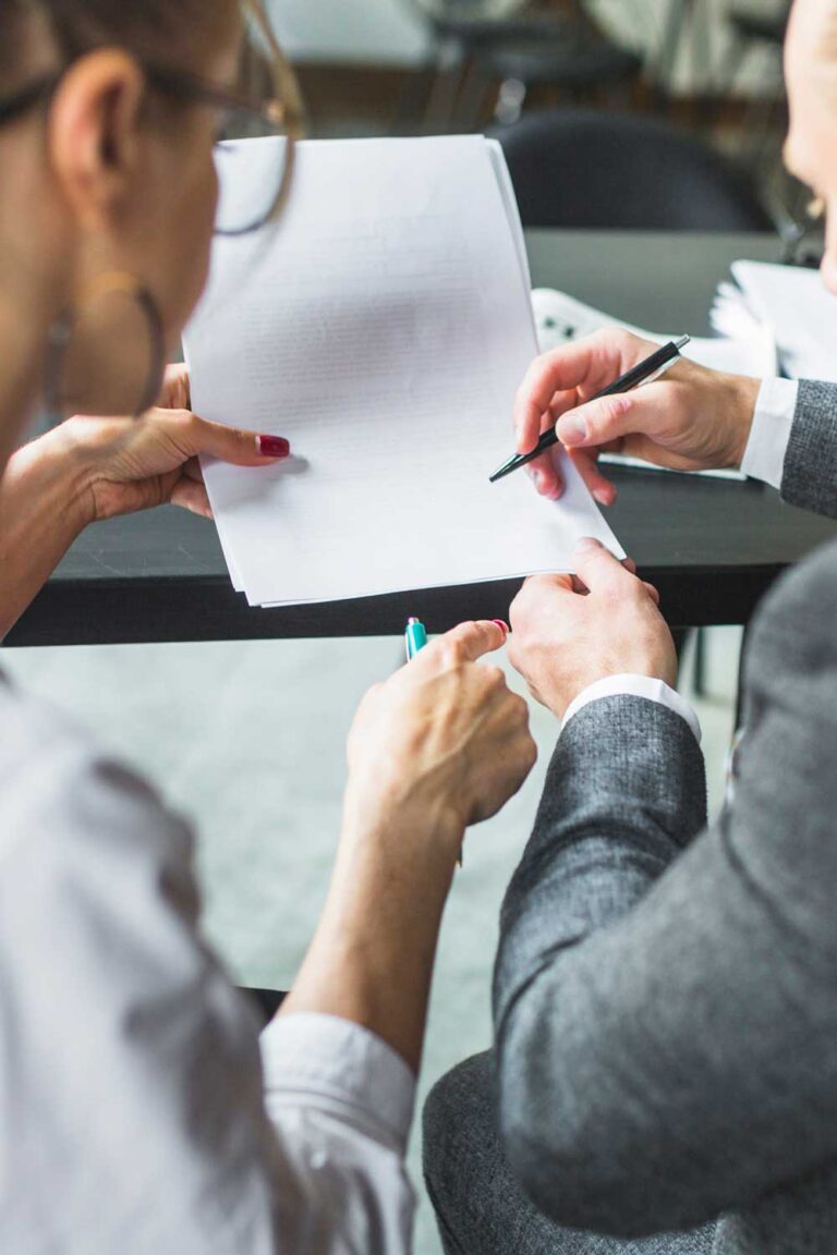 Zwei Personen diskutieren über Display-Werbung, während sie an einem Tisch Dokumente mit Stiften durchsehen.